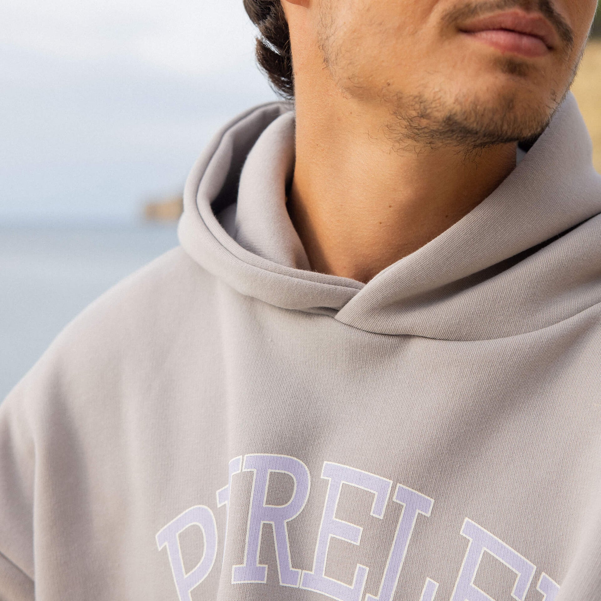 Graue PURELEI Kapuzenjacke mit weißem Logo, lässig und modern, perfekt für entspannte Tage.