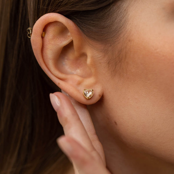 Roségoldene Ohrringe mit herzförmigem Design, getragen mit sanftem Licht, PURELEI.