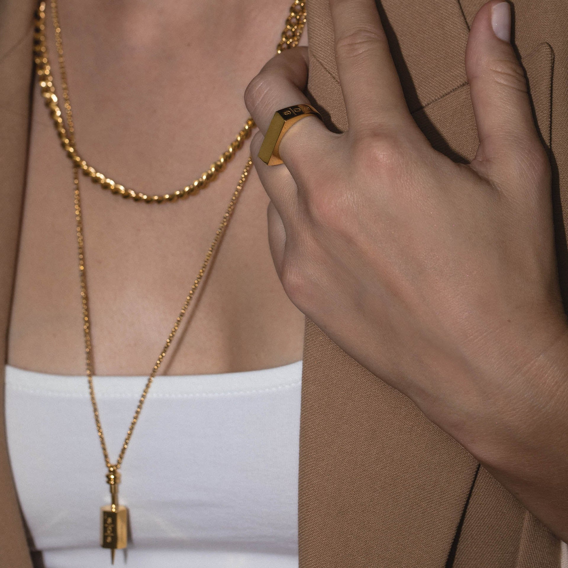 Square Ring aus 18K vergoldetem Edelstahl mit seitlichem 808 Logo, getragen an Hand elegant gestylt von PURELEI.