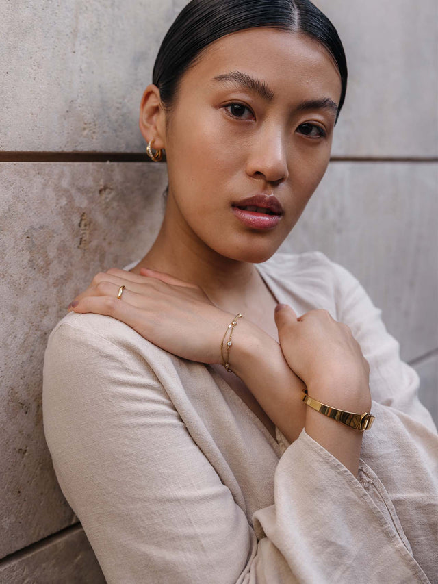 Elegantes, roségoldenes Armband und zarte Ohrringe von PURELEI, getragen in natürlicher Umgebung.