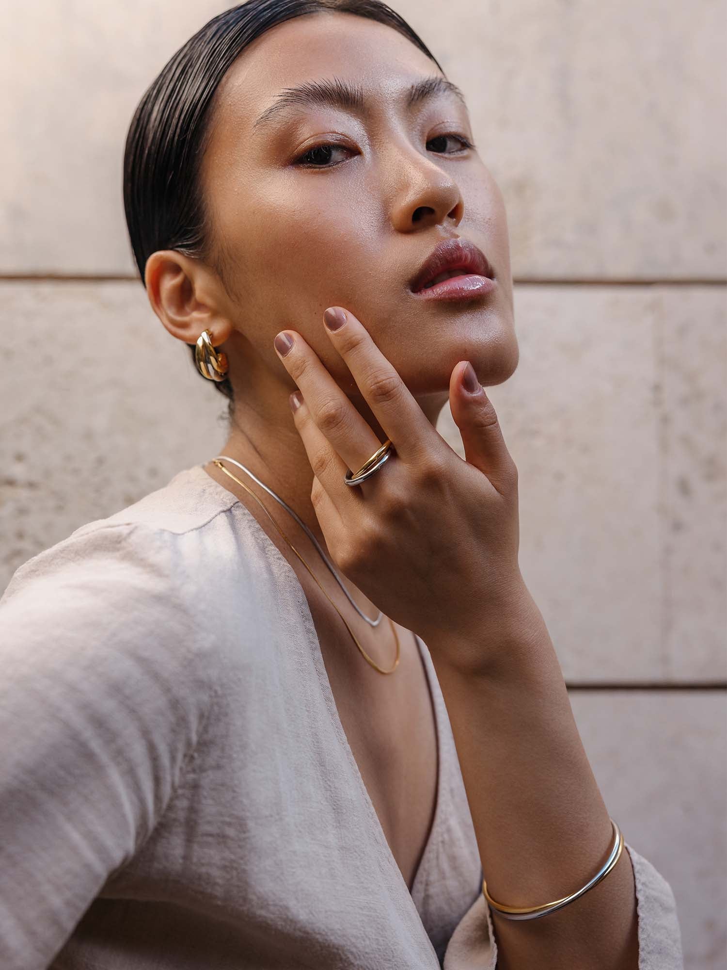 Elegante, roségoldene PURELEI Ohrringe und Armband, getragen mit natürlichem Look.