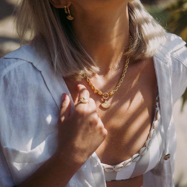 Goldene Kette mit Muschel-Anhänger, getragen in sonniger Atmosphäre – PURELEI.