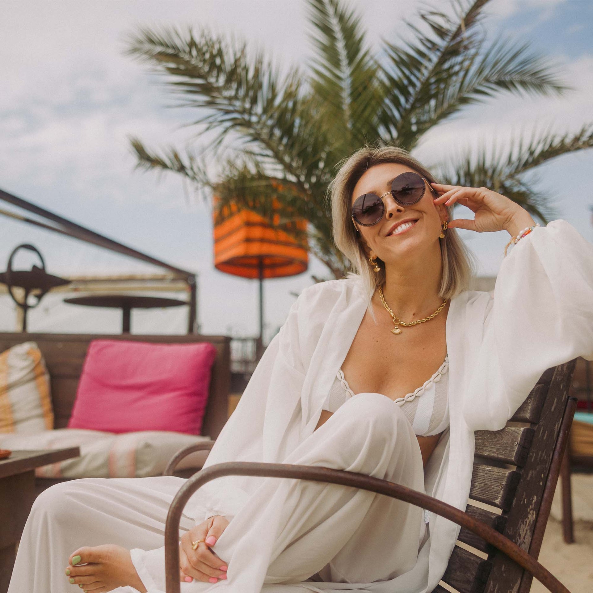 Feminine PURELEI Kette mit Muschel-Anhänger, getragen in tropischer Atmosphäre.