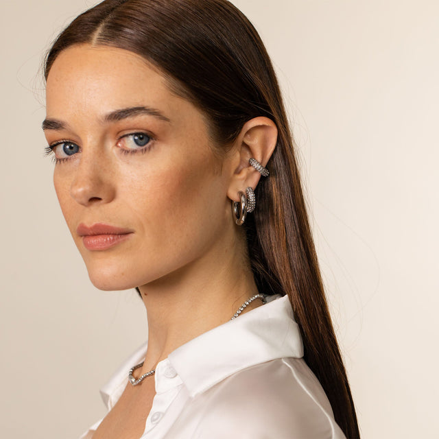 Silberne Creolen und Ohrstecker von PURELEI, elegant und modern, getragen mit einem weißen Hemd.