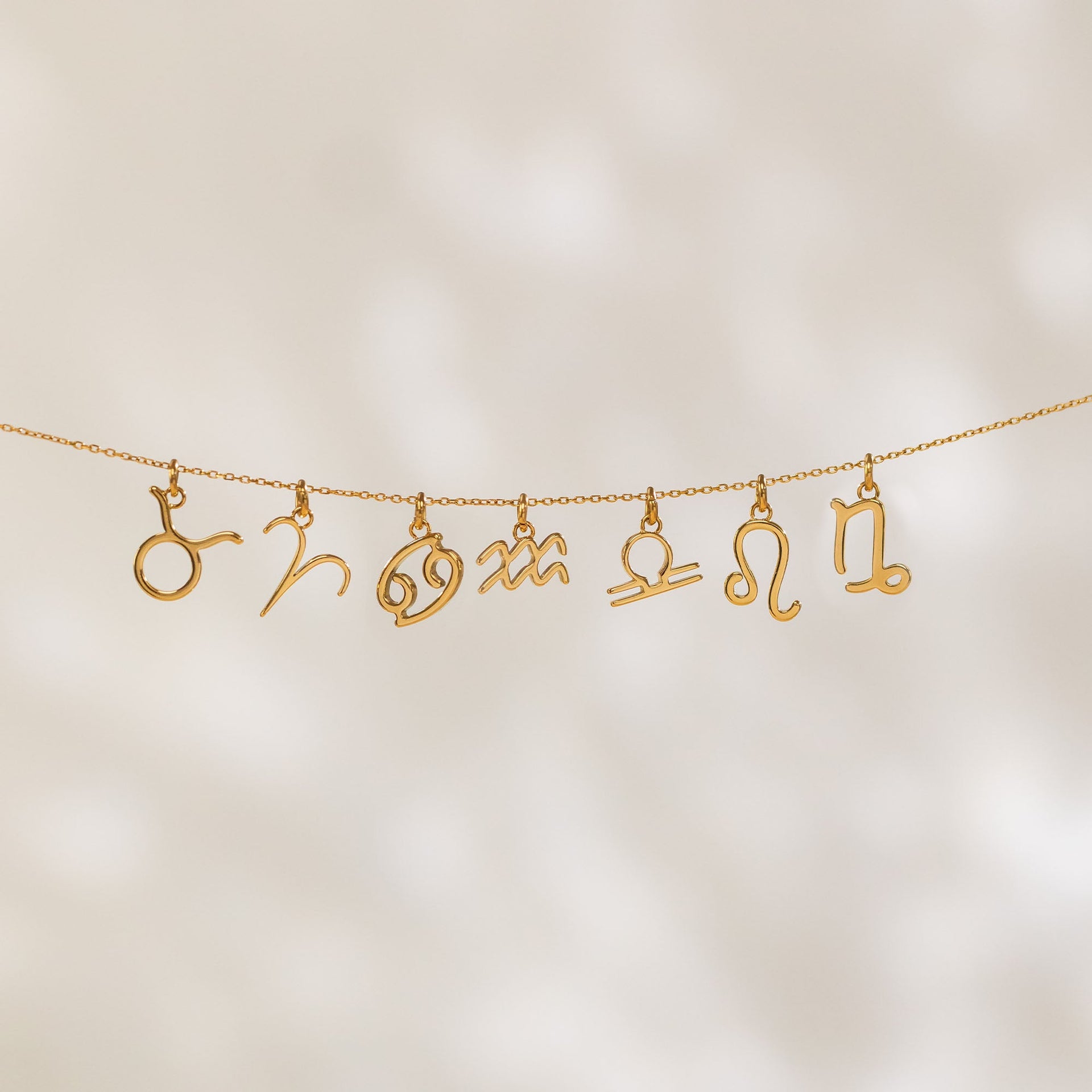 PURELEI Krebs Zodiac Charm aus 18K Gold vergoldetem Edelstahl, filigran und elegant in warmem Licht präsentiert