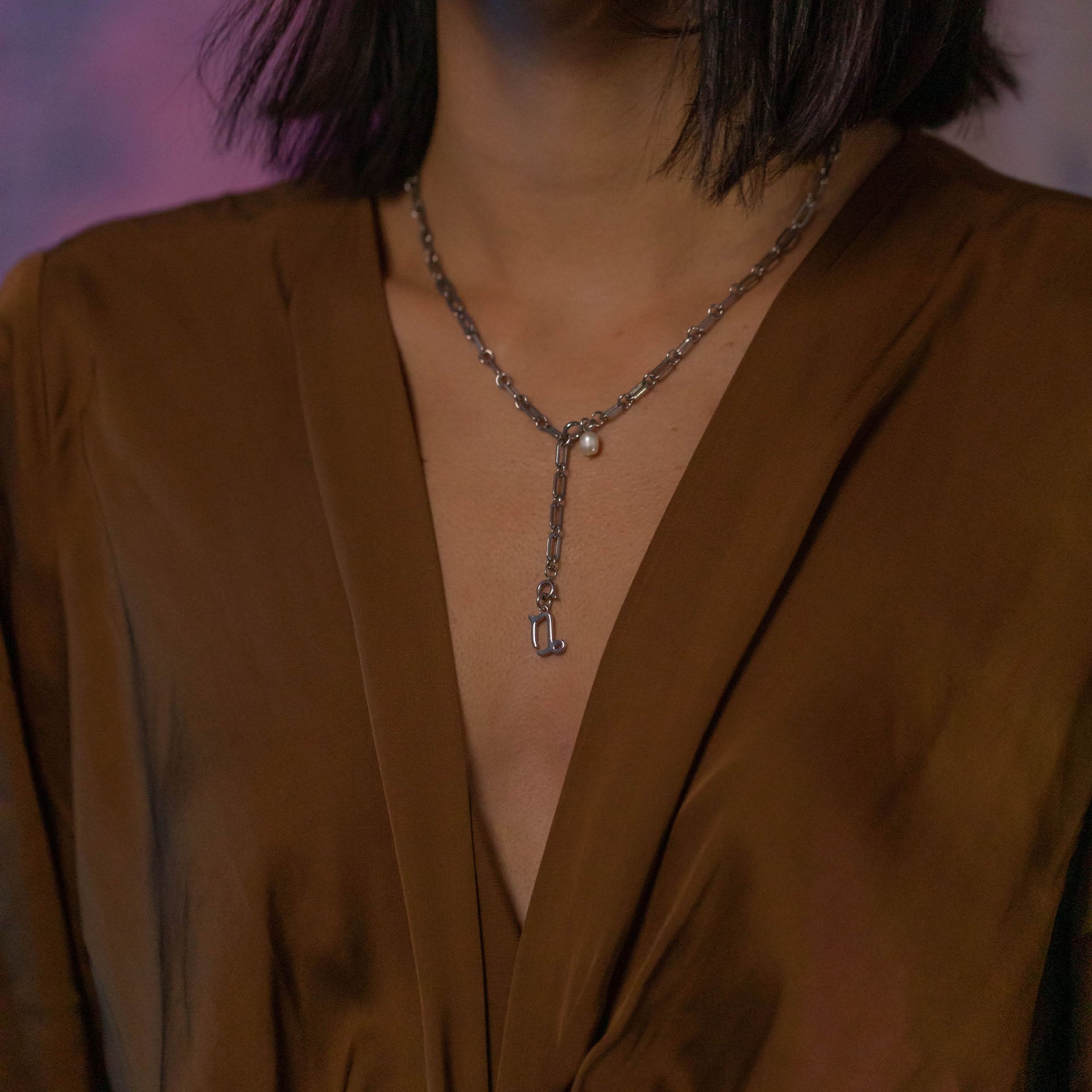 Steinbock Zodiac Charm aus nickelfreiem Silber, filigran getragen zu eleganter Seidenbluse, PURELEI Ästhetik.