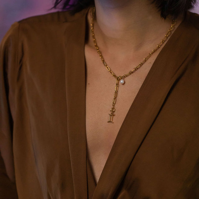 PURELEI Zwilling Zodiac Charm aus 18K Gold mit Perlen-Detail, elegant am Dekolleté getragen, femininer Island-Spirit