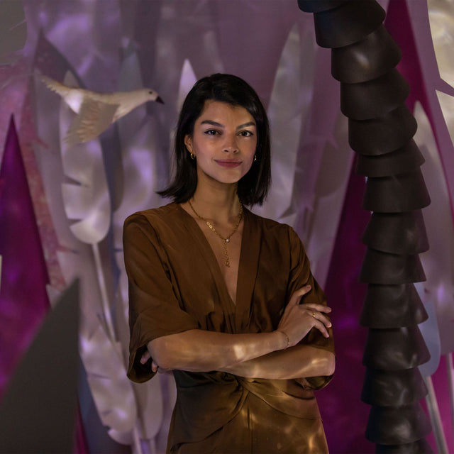 Zodiac Charm Kette von PURELEI in Gold mit schimmernder Süßwasserperle, elegant getragen vor tropischem Hintergrund